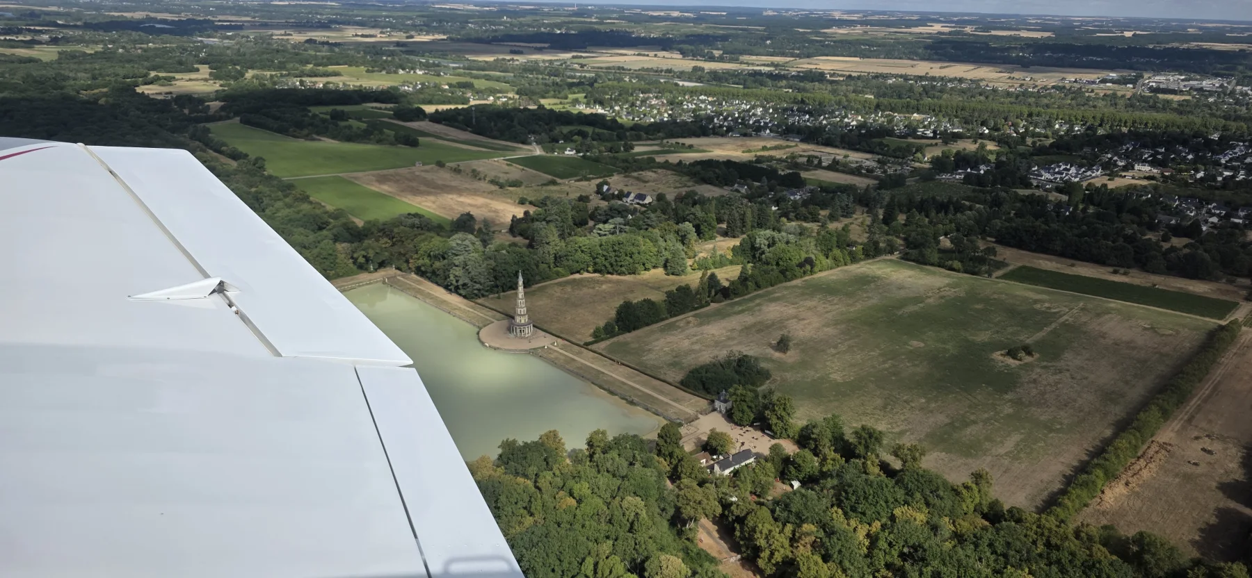 Aile blanche d’un avion au-dessus des paysages de Touraine