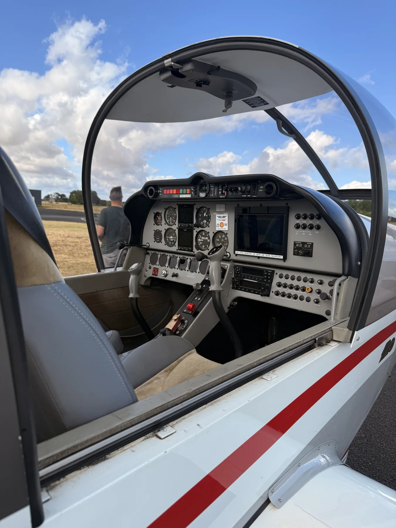 Cockpit ouvert d’un Robin DR401 stationné sur le parking